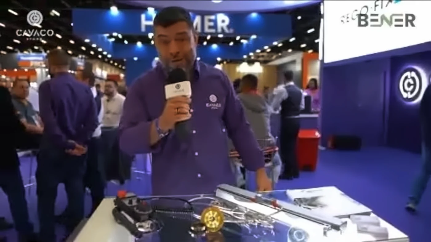 Apresentador com camisa e microfone da Cavaco Store mostrando ferramentas de usinagem no balcão do estande