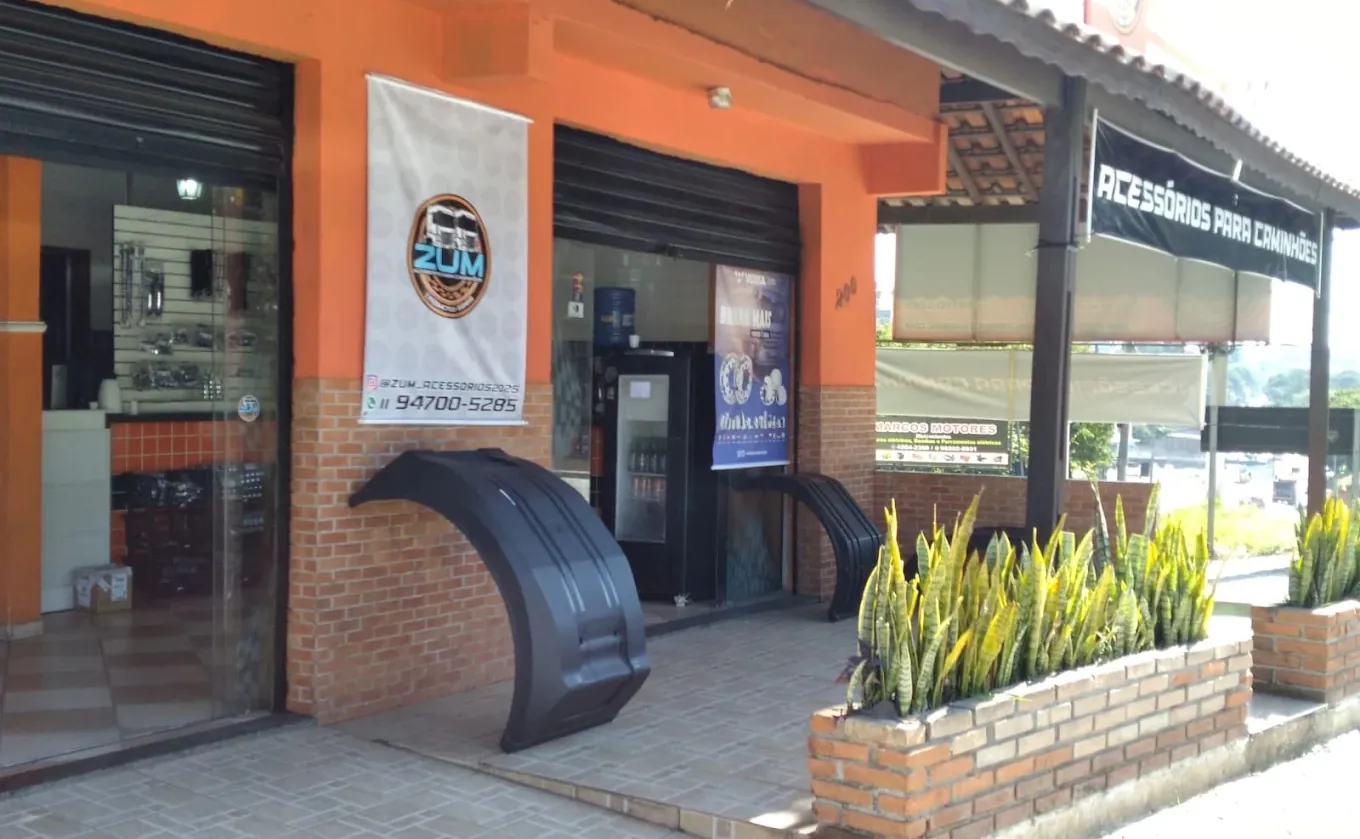 Fachada da loja ZUM Acessórios para Caminhões, com banner da marca e para-lamas expostos na calçada